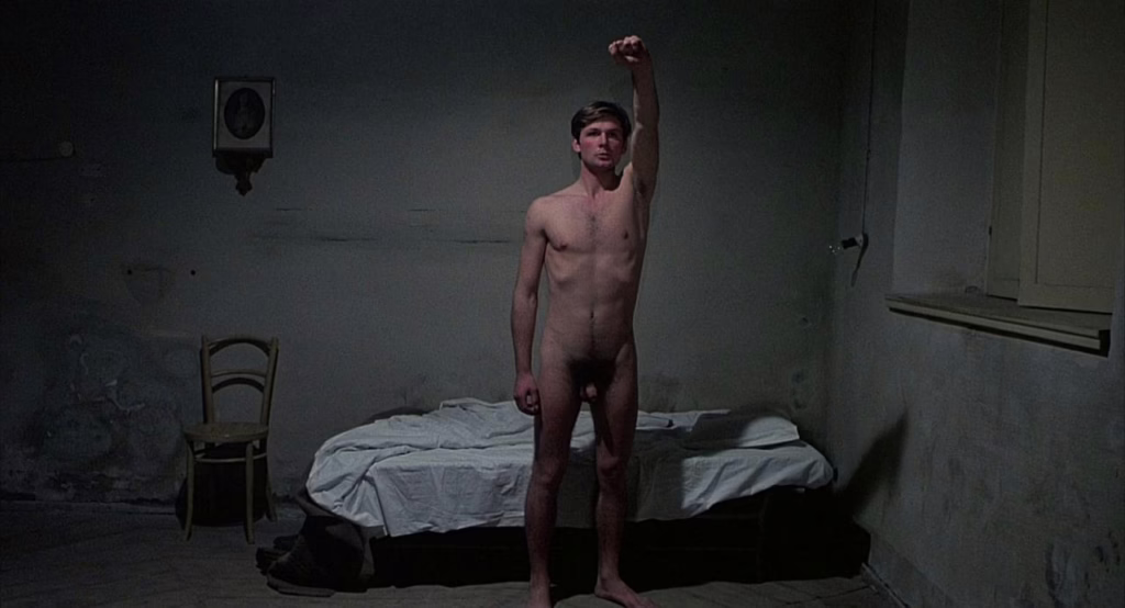 A still from Salò depicting Ezio raising his fist in protest against fascist authorities.